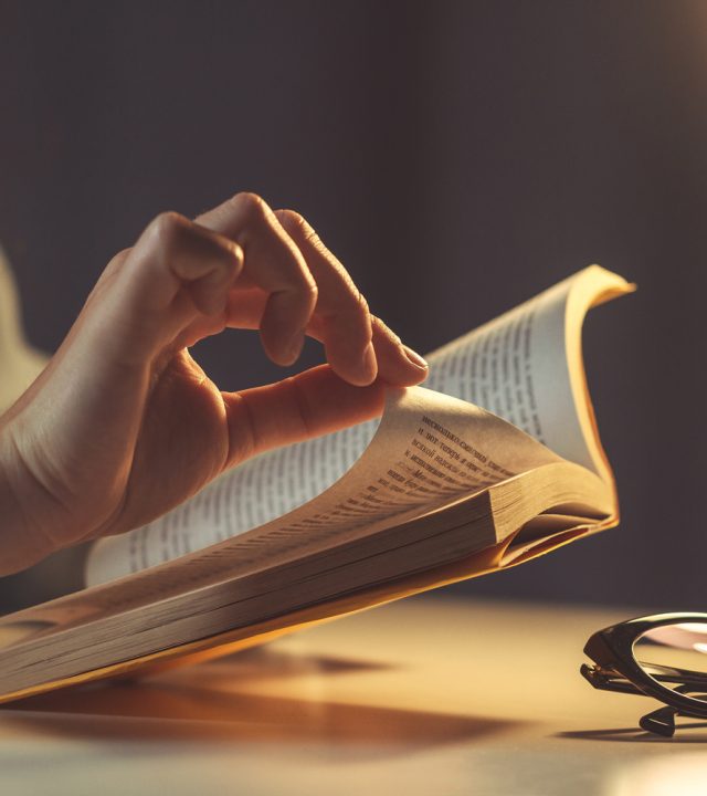 woman-reading-book-evening-home-close-up